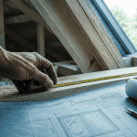 Artisan mesurant dimension Velux sur toiture